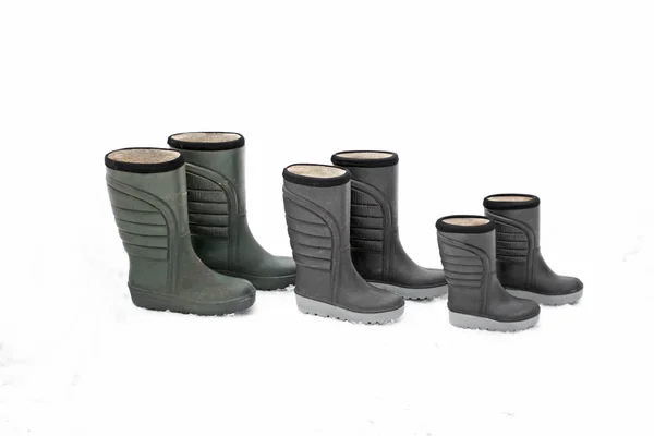 Three pair of dirty winter boots different sizes standing in row on snow. Seasonal shoes for all family mother, father and child. — Stock Photo, Image