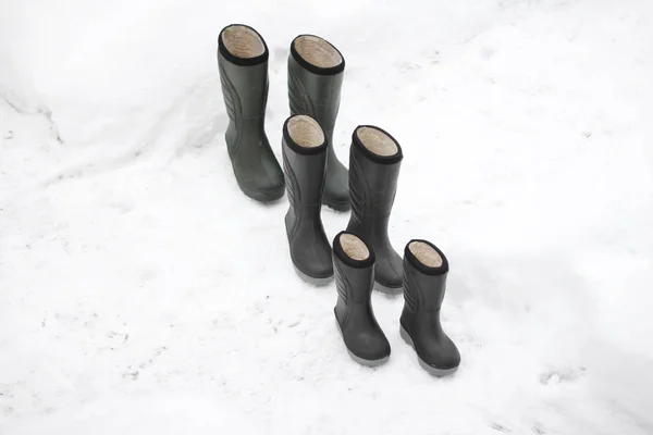 Three pair of winter boots different sizes standing on snow. Seasonal shoes for all family, adult and and child footwear. — Stock Photo, Image