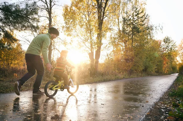 Vater bringt seinem kleinen Kind das Fahrradfahren im Herbstpark bei. glückliche Familienmomente. Zeit mit Vater und Sohn. Aufrichtiges Lebensstil-Image. — Stockfoto