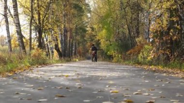 Baba ve oğul sonbahar parkında eğleniyor. Bisiklet pratiği yapan tatlı çocuk, babası onun yanında koşuyor. Mutlu aile anları. Gizli yaşam tarzı görüntüleri. 