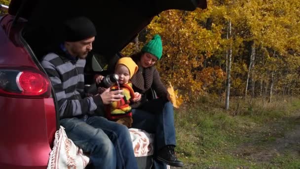 快乐的家庭在秋天的森林里度过了一天的户外休息 母亲和孩子坐在汽车行李箱里 用热水瓶喝茶 户外野餐 秋天的旅行 — 图库视频影像