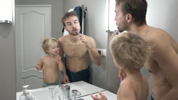 爸爸教小孩刷牙洗脸 爸爸和他的小儿子早上在浴室刷牙 儿童的牙齿护理 家庭在家里 — 图库视频影像