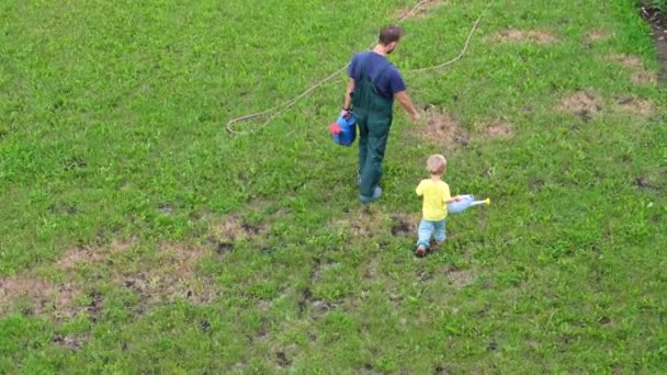 Légi Lövés Apa Kisfia Kertészek Öntözőkanna Kezükben Sétáló Zöld Gyep — Stock videók