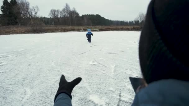 一家人寒假在结冰的湖上玩得开心 小儿子跑去接他的父亲 爸爸接了孩子 拥抱了他 吻了他 生活方式 — 图库视频影像