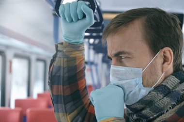 Hastalık salgını, Coronavirus covid-19 salgınını durdurmak, virüs koruması, karantina. Tıbbi koruyucu maskeli ve eldivenli yetişkin bir adam toplu taşıma araçlarında öksürüyor. Kendini koru..