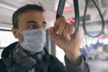 Hastalık salgını, Coronavirus covid-19 salgını, virüs koruması. Yüzünde tıbbi koruyucu maske olan yetişkin bir adamın portresi toplu taşıma aracının içinde duruyor..