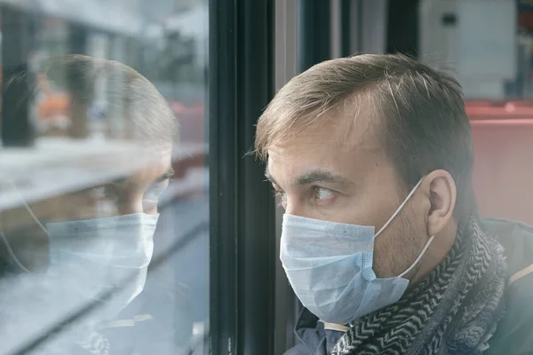 Hastalık salgını, Coronavirus covid-19 salgını, virüs koruması. Toplu taşıma aracında yüzü tıbbi koruyucu maskeli korkmuş yetişkin bir adamın portresi..