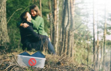 Dijital detoks, birbirine aşık çiftler doğada akıllı telefonlar olmadan zaman geçirirler. Erkek ve kadın parkta ya da ormanda oturuyor, sarılıyor ve öpüyor, kutuda ön planda yasaklama işareti olan aletler var.. 