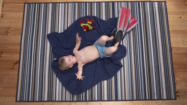 梦想着大海 2020年暑假没有旅行 滑稽的小男孩戴着鳍躺在公寓的地板上 模仿着游泳 在家里独自潜水 检疫家庭活动 — 图库视频影像