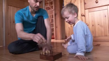 Çocuk ve baba evde tic-tac-toe oynuyorlar. Oğlum, babam ve masa oyunu. Beraberlik olduğu için el sıkışıyorlar. Ebeveynler çocuklarla vakit geçirirken karantina ve kendini izole etme.