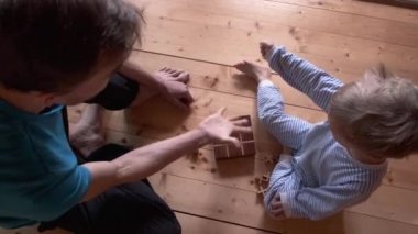 Çocuk ve baba evde masa oyunu oynuyorlar. Oğlu ve babası taş, kağıt, makas, sonra da tik, toynak oynuyorlar. Karantina ve kendini izole etme sürecinde ebeveynler çocuklarla vakit geçirir. Yukarıdan görüntüle.