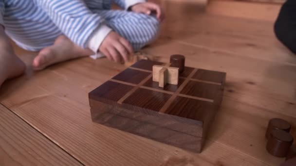 ボード木製のゲームチックタックつま先を閉じます 子供と父親が家で遊んでいる 息子が勝つ 親は隔離および自己隔離の間子供との時間を使う 家族活動 — ストック動画