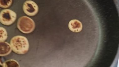 Pişirilmiş küçük krep gevreği pişirme süreci - moda karantina gıdaları. Gözlemeler tavaya atıldı ve ağır çekimde devrildi. Ev yapımı kahvaltı..