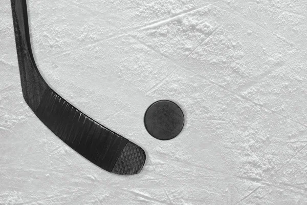 Černá hokejku a PUK na ledě — Stock fotografie