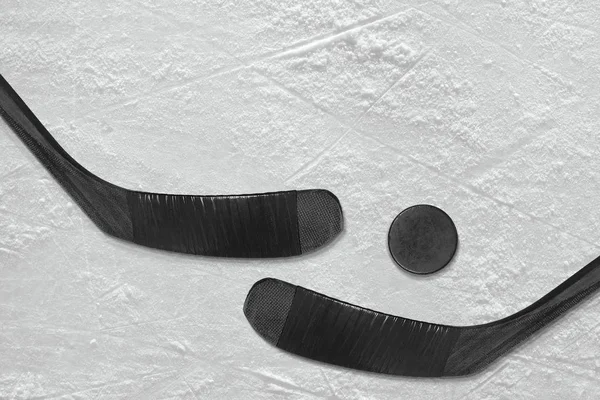 Hockey puck and a pair of black sticks on the ice — Stock Photo, Image