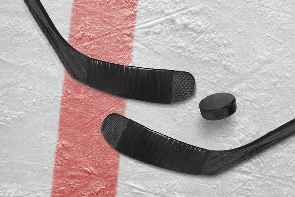 Palo de hockey y disco en el hielo —  Fotos de Stock