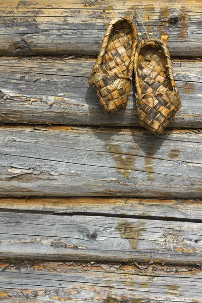 Russische bast schoenen op een houten muur — Stockfoto