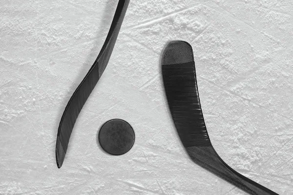 Two black sticks and ice hockey puck — Stock Photo, Image