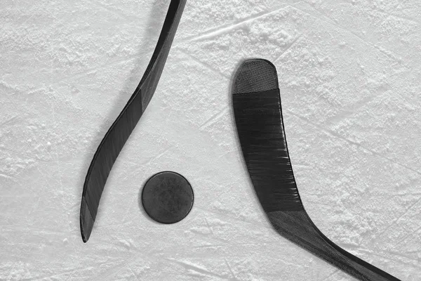 两个黑色的棍棒和冰上曲棍球冰球 免版税图库照片