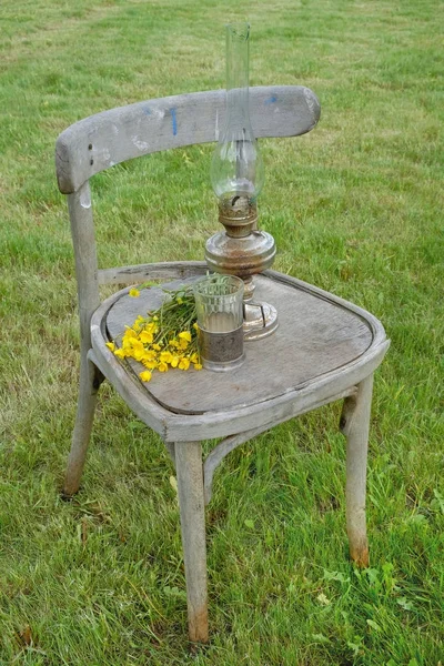 Lampada a cherosene, bicchiere di vetro e un mazzo di fiori su un vecchio c — Foto Stock