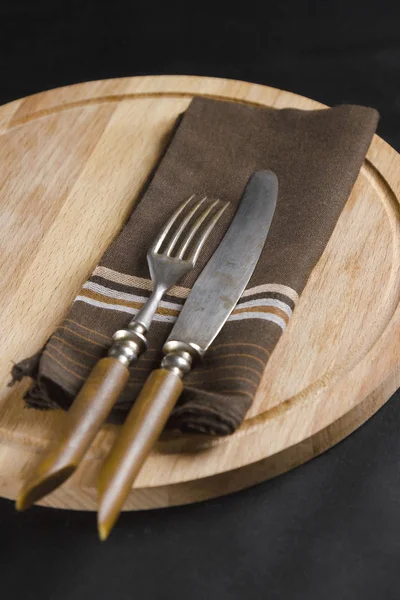 Velhos garfos e facas em uma placa de corte — Fotografia de Stock