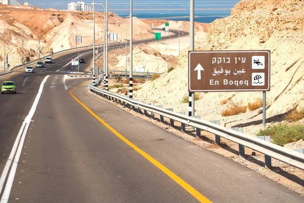 イスラエル- 2017年9月22日: Ein Bokek Beachへの道路標識。遠くの砂漠と死海への道 — ストック写真