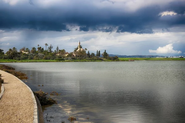 位于塞浦路斯拉纳卡盐湖西岸的Hala Sultan Tekke或Umm Haram清真寺 蓝色的乌云雨天 湖畔的小路 — 图库照片