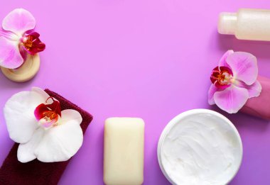 Sabun, havlu, krem ve hijyen ürünleri, leylak arkaplanda beyaz ve leylak rengi çiçeklerle süslenmiş. Spa konsepti