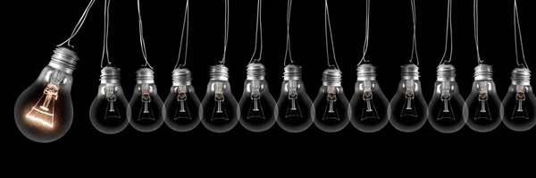 Group of dark and shining light bulbs in a row isolated on black background. Concept of Idea, Innovation, Success and Creativity.