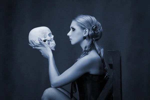 Beautiful woman with a skull low key portrait — Stock Photo, Image