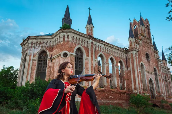 Woman musician playing the violin near an old castle — Stock Photo, Image