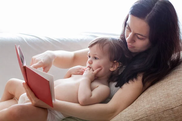 Mãe lendo um livro para sua filha dentro de casa — Fotografia de Stock