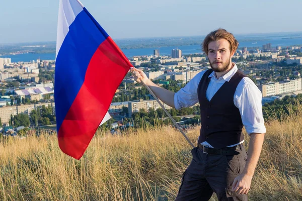 ロシア人の男性が市サラトフ ロシアに近いロシアの旗を保持しています — ストック写真