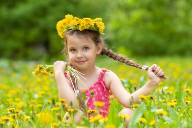 5 yaşındaki kız. Çayırlarda karahindibalarla oynuyorlar.