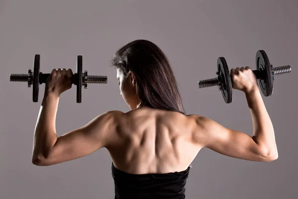 Girl in sexy black dress lifting weights — Stock Photo, Image