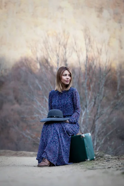 Симпатичная девушка с винтажным чемоданом на грязи — стоковое фото
