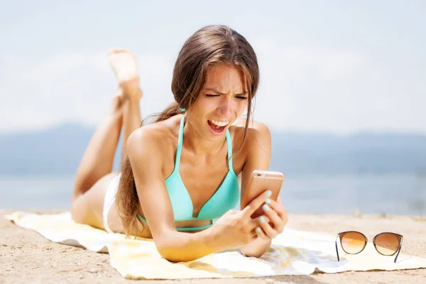 Verrast meisje met telefoon op een strand — Stockfoto