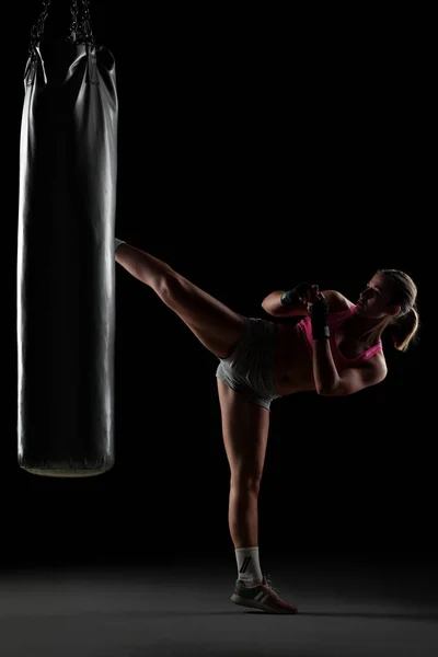 Девушка бьет боксерскую сумку — стоковое фото