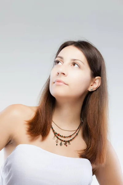 Překvapený bruneta dívka, která nosí náhrdelník s obecné symboly — Stock fotografie