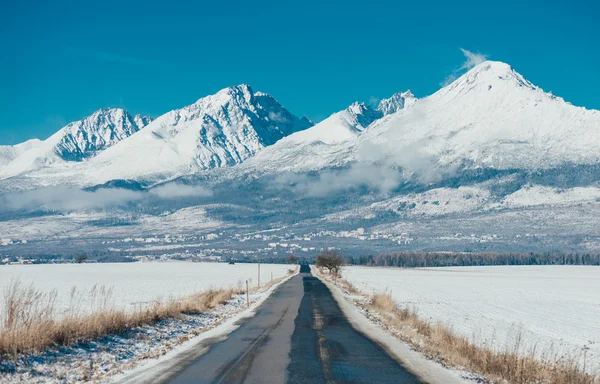 Estrada e neve coberto de montanhas — Fotografia de Stock