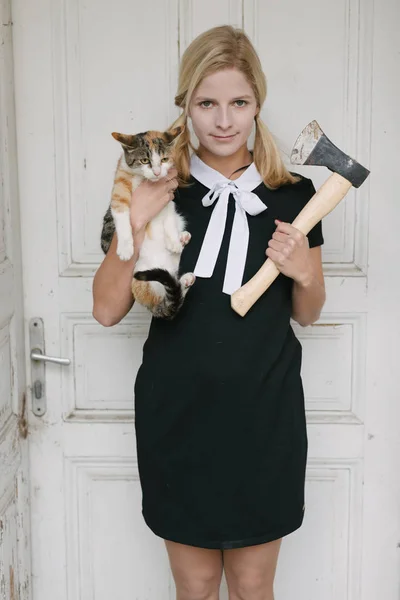 Griezelig blonde vrouw met bijl en kat — Stockfoto