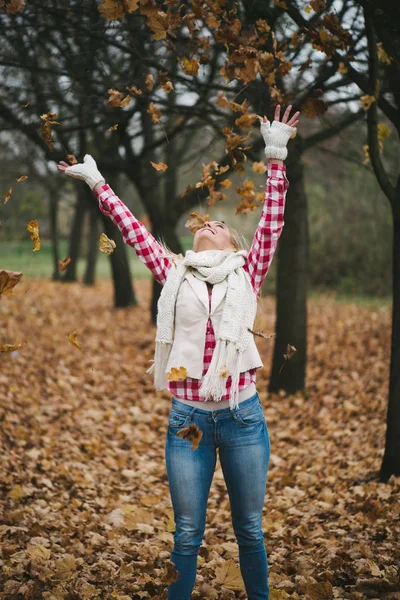 Ευτυχισμένη γυναίκα παίζει με φθινοπωρινά φύλλα — Φωτογραφία Αρχείου