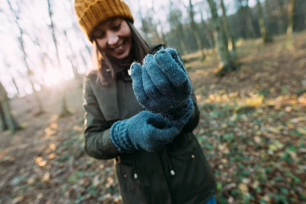 Lachende vrouw in gebreide muts zet handschoenen — Stockfoto