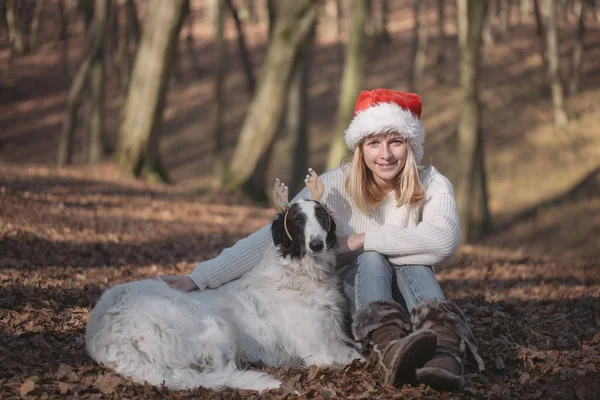 Mujer joven en sombrero de santa con lindo perro —  Fotos de Stock