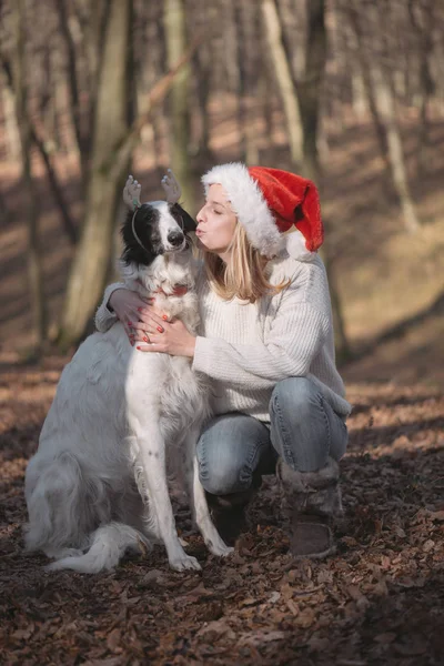 Молодая женщина в шляпе Санты с симпатичной собакой — стоковое фото