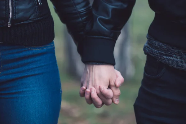 Konceptuell bild av kvinnliga och manliga händer tillsammans. Ungt par i kärlek promenader i parken höll händer. — Stockfoto