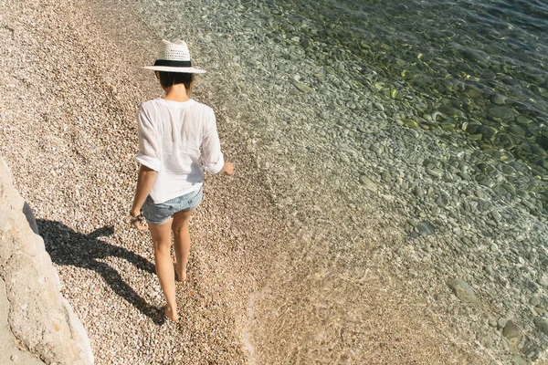 Mujer caminando en la playa rocosa — Foto de Stock