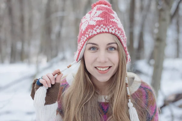 Winterporträt einer jungen schönen blonden Frau mit Strickmütze. Schneefall Winter Beauty Fashion Konzept. verschneiter Wald im Hintergrund. — Stockfoto