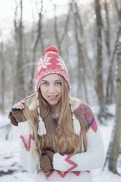 Winterporträt einer jungen schönen blonden Frau mit Strickmütze. Schneefall Winter Beauty Fashion Konzept. verschneiter Wald im Hintergrund. — Stockfoto