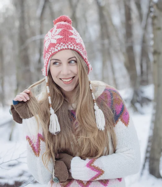 Şapka giyen genç güzel sarışın kadın portresi kış ördü. Kış Güzellik moda kavramı kar yağıyor. Arka plan üzerinde karlı orman. — Stok fotoğraf